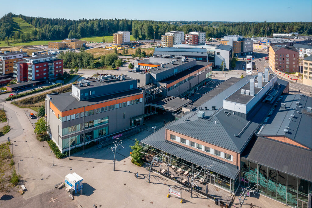 Harmaasävyinen kaksikerroksinen toimitilakiinteistö, jonka ympärillä Taidetehtaan muita rakennuksia.